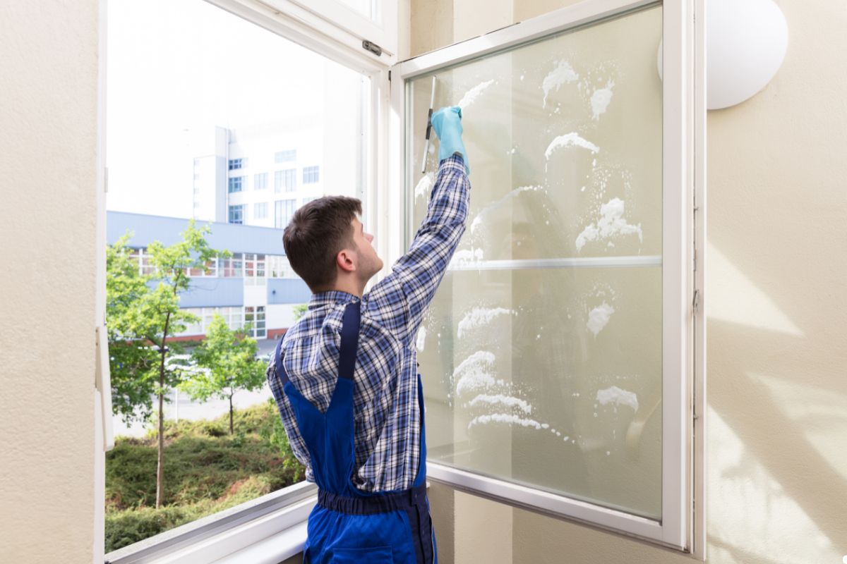 A man using a squeegee to clean a large window, focused on removing streaks for a clear view. 